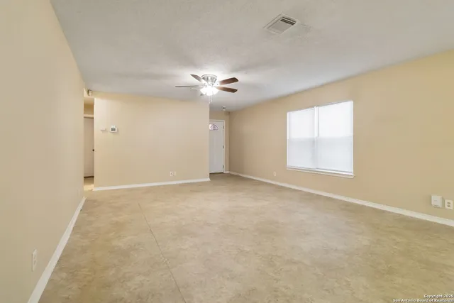 an empty room with a ceiling fan and a window