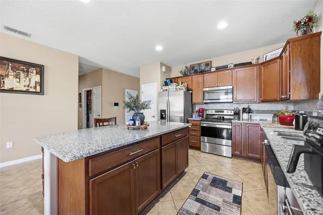 a kitchen with stainless steel appliances granite countertop a sink dishwasher stove refrigerator and cabinets