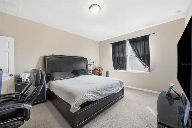 a bedroom with a bed and a flat tv screen on a dresser