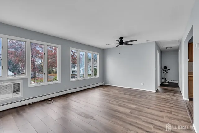 a view of an empty room with a window and wooden floor