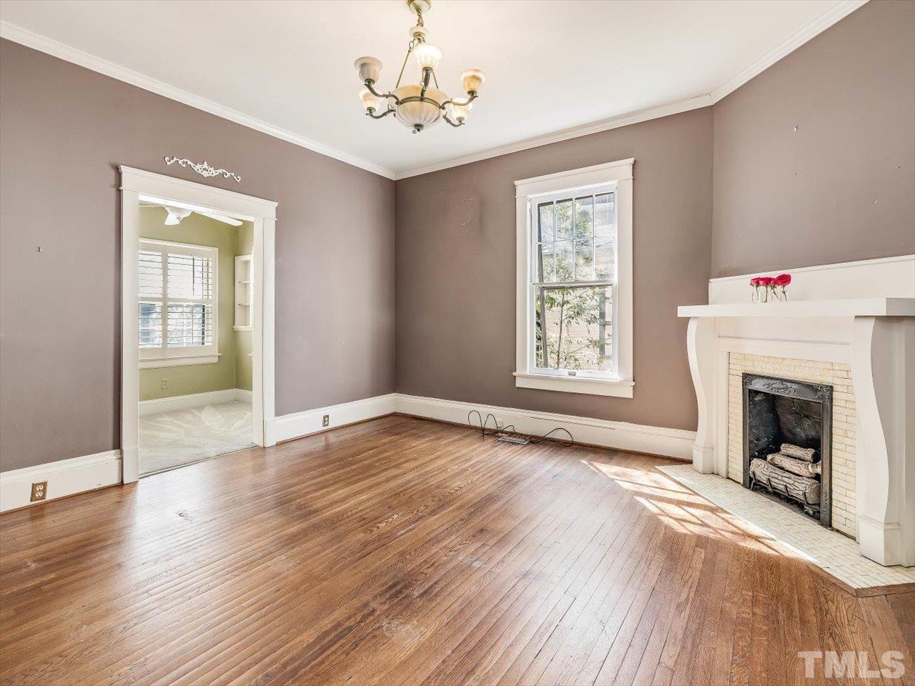 118 Hawthorne Road Raleigh, NC 27605 - Photo 22 of 42 a view of an empty room with wooden floor fireplace and a window