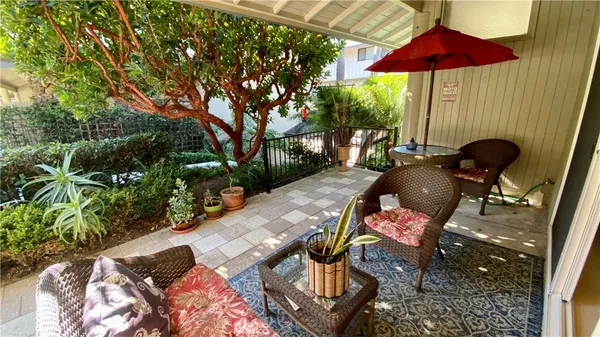 a patio with tables and chairs under an umbrella