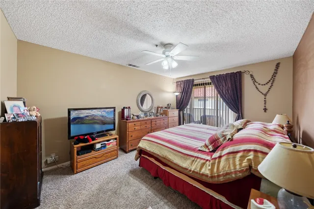 a bedroom with a bed a dresser and flat screen tv