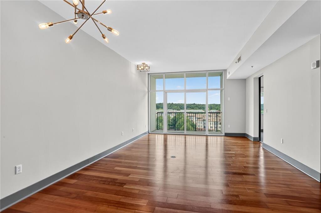 4561 Olde Perimeter Way, Unit 1207 Atlanta, GA 30346 - Photo 3 of 32 a view of an empty room with wooden floor and a window