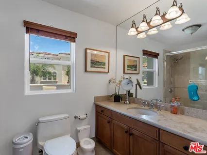 a view of a patio with couches table and chairs under an umbrella with palm trees