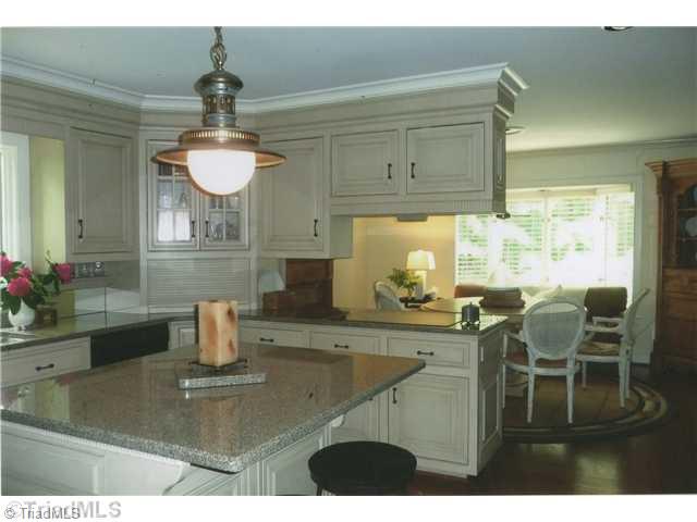 8262 Ballard Road Colfax, NC 27235 - Photo 6 of 16 Kitchen. View from kitchen to dining room area with fireplace and bay window features granite counter tops and a built-in 41x74 Viking refrigerator