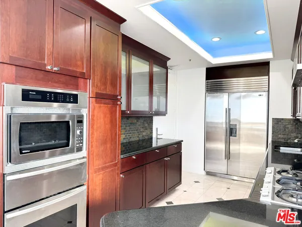 a kitchen with stainless steel appliances granite countertop a refrigerator a stove and a sink with wooden floor