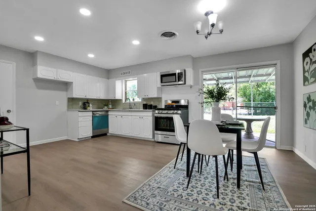 a kitchen with a table chairs microwave and cabinets