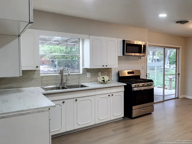 a kitchen with stainless steel appliances granite countertop a stove a sink and a microwave