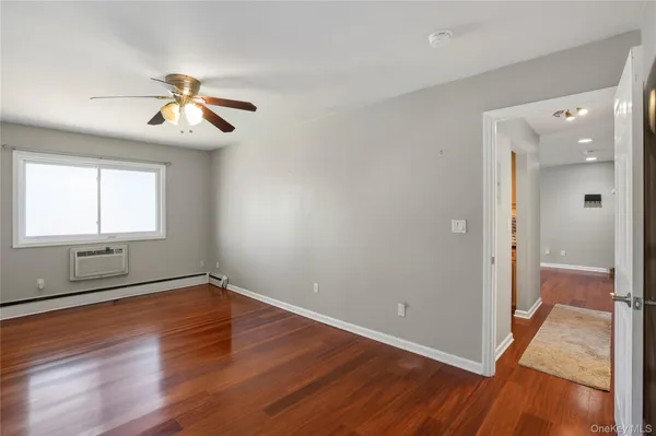 an empty room with wooden floor fan and windows