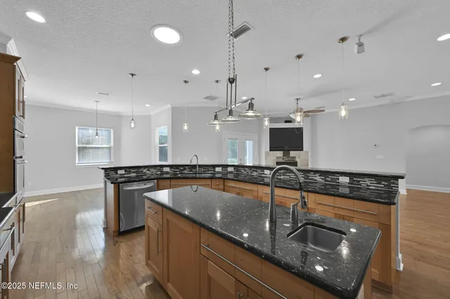 a kitchen with stainless steel appliances granite countertop a sink a stove and a wooden floor