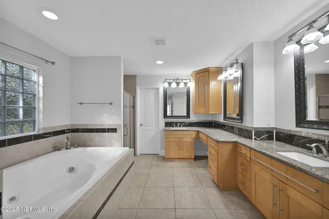 a large spacious bathroom with a tub sink shower and mirror