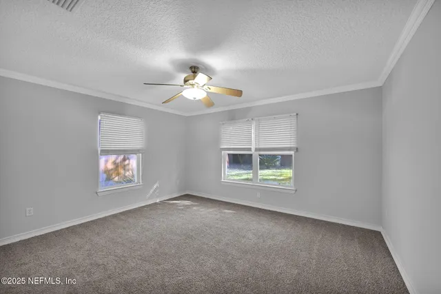 an empty room with windows and chandelier fan