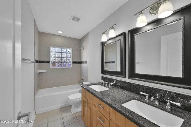 a bathroom with a granite countertop sink double vanity and a bathtub
