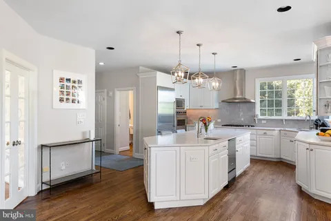 a large kitchen with kitchen island white cabinets and stainless steel appliances