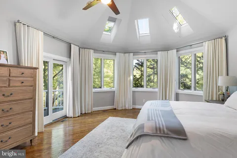a bed sitting in a spacious bedroom next to a window and a chandelier