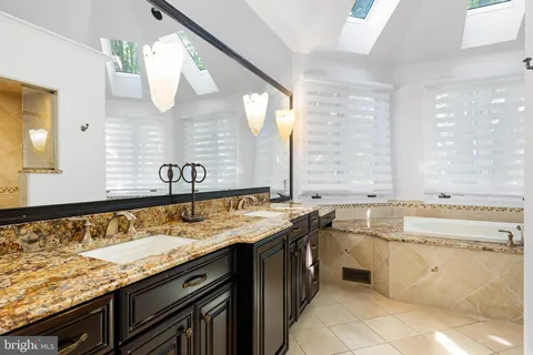 a bathroom with a granite countertop sink and a large mirror