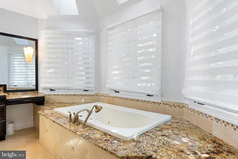 a bathroom with a tub a sink and a window