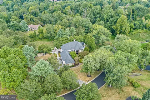 an aerial view of residential house with outdoor space and trees all around