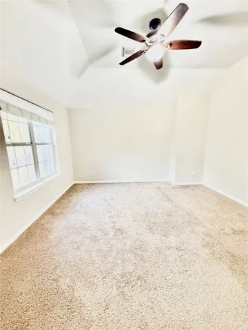 an empty room with a window and ceiling fan