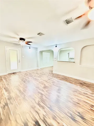 a view of empty room with wooden floor and fan