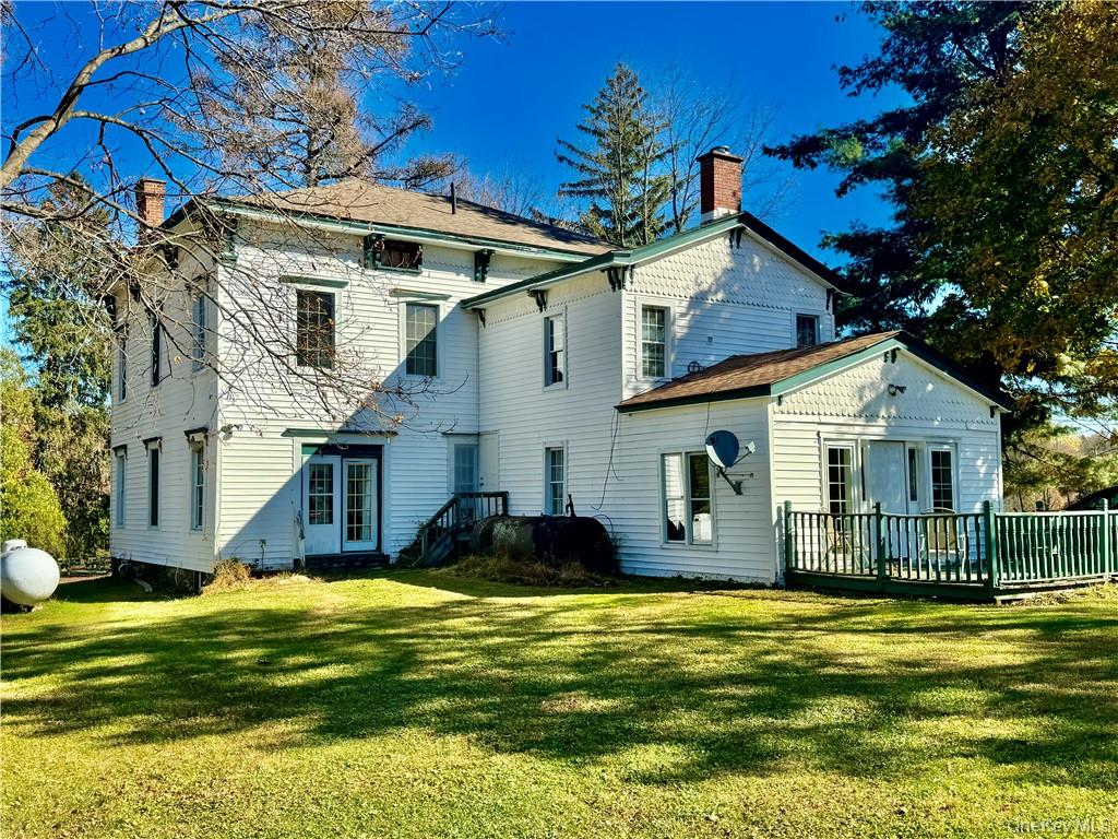 Rear view of house featuring a yard and a wooden deck