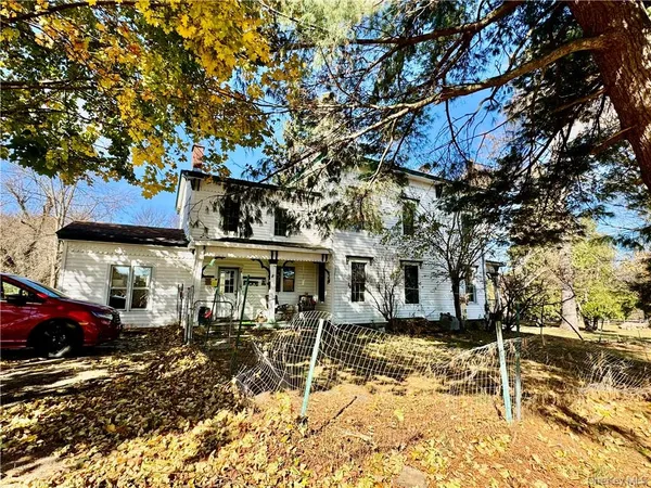 a front view of a house with a large tree