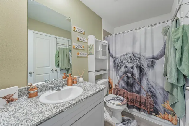 a bathroom with a granite countertop toilet a sink and a shower curtain