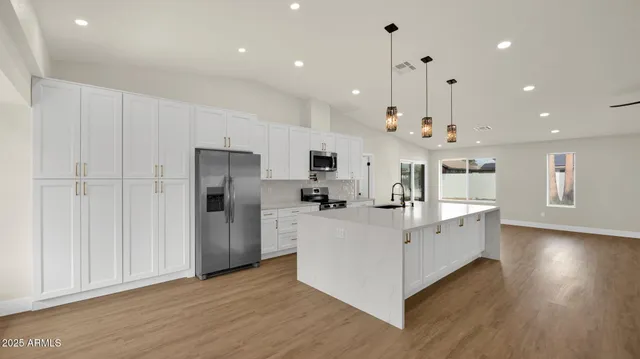 a large white kitchen with lots of counter space and stainless steel appliances