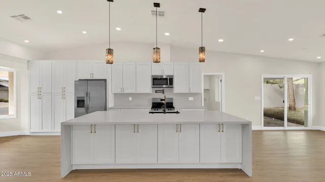 a kitchen with kitchen island a counter top space appliances and cabinets