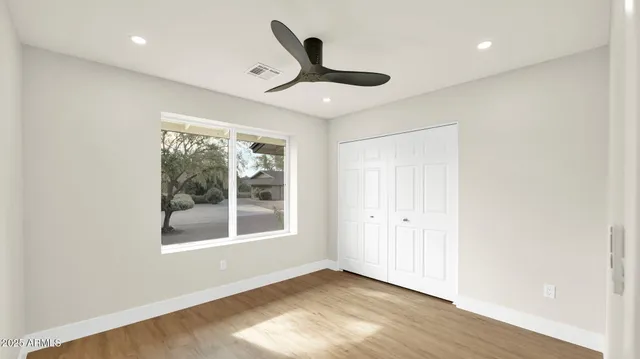 a view of empty room with wooden floor and fan