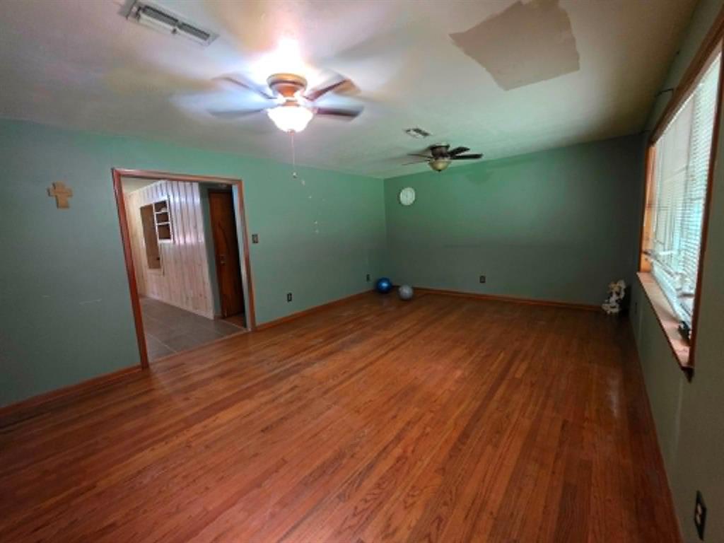 4514 West Loop 281 Longview, TX 75604 - Photo 17 of 36 Spacious interior room featuring wood-finish flooring, light green painted walls, and multiple ceiling fans for air circulation