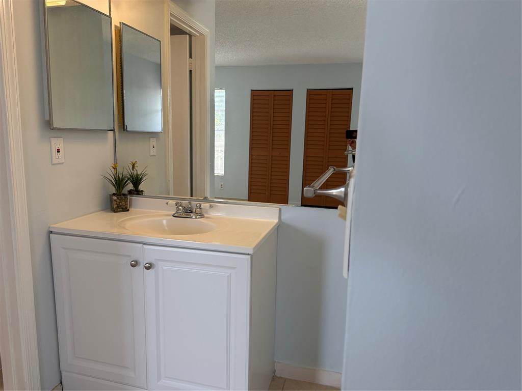9930 Twin Lakes Drive, Unit 7L Coral Springs, FL 33071 - Photo 23 of 39 a bathroom with a granite countertop sink and a mirror