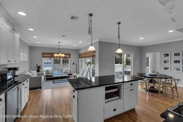 a kitchen with stainless steel appliances granite countertop a stove a sink a dining table and chairs with wooden floor