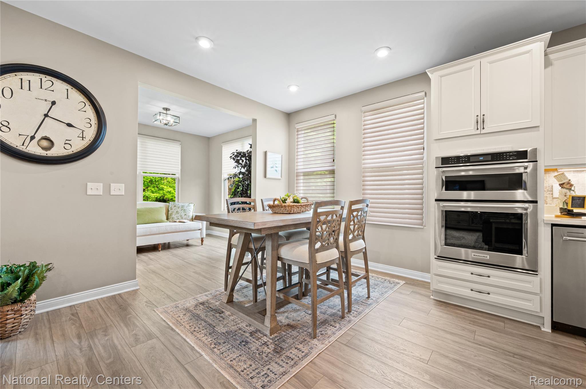 48796 Windfall Road Novi, MI 48374 - Photo 5 of 30 Kitchen and dining area featuring wood-finish flooring, recessed lighting, double wall ovens, white cabinetry, and horizontal window blinds