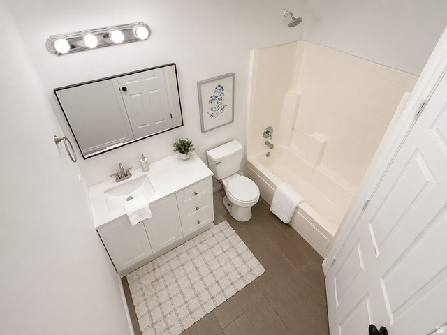 30 West 7500th Street South, Unit 18 Midvale, UT 84047 - Photo 9 of 14 Bright bathroom featuring a single-sink vanity with white cabinetry and a rectangular mirror, a toilet, a full bathtub with an integrated shower, and dark gray tile flooring
