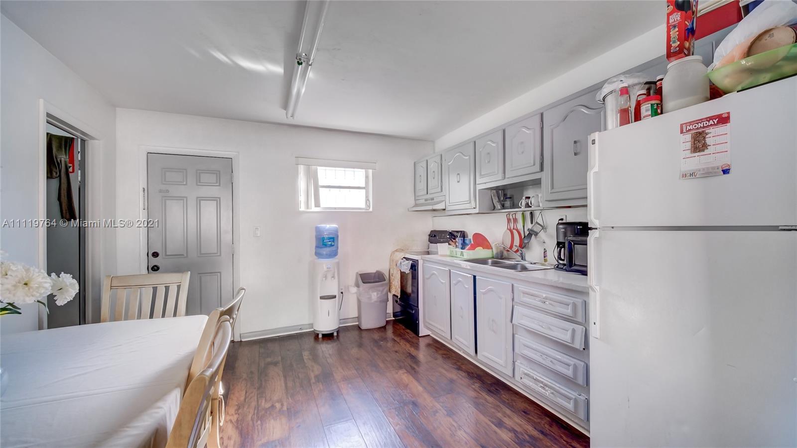 285 Northwest 97th Street Miami, FL 33150 - Photo 16 of 28 a kitchen with a refrigerator a stove top oven and a wooden floor
