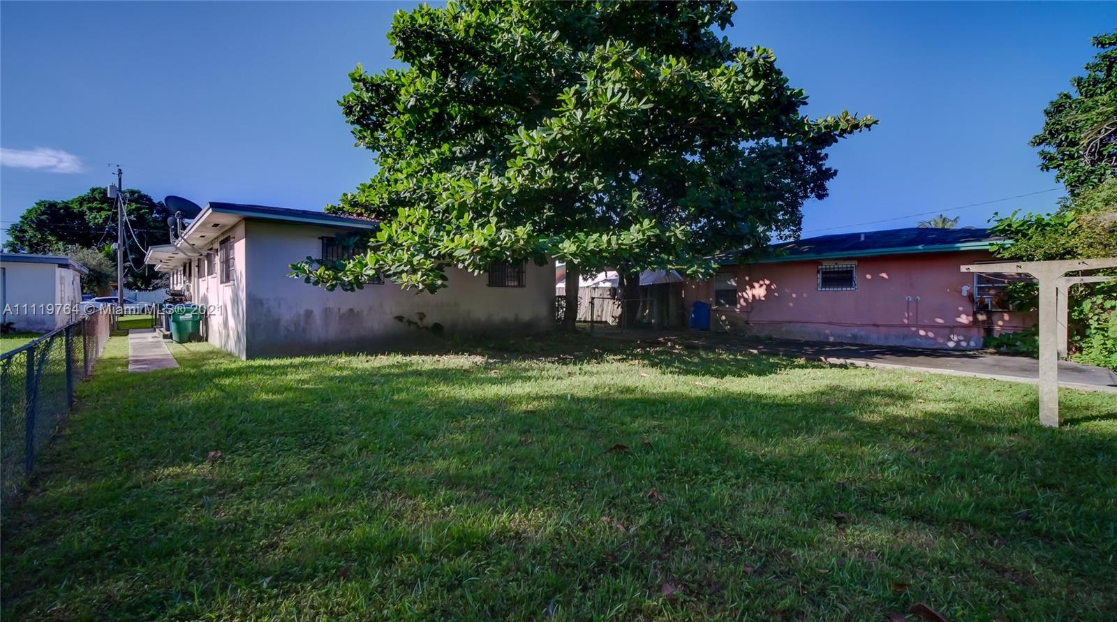 285 Northwest 97th Street Miami, FL 33150 - Photo 23 of 28 a view of a backyard with table and chairs potted plants and large tree