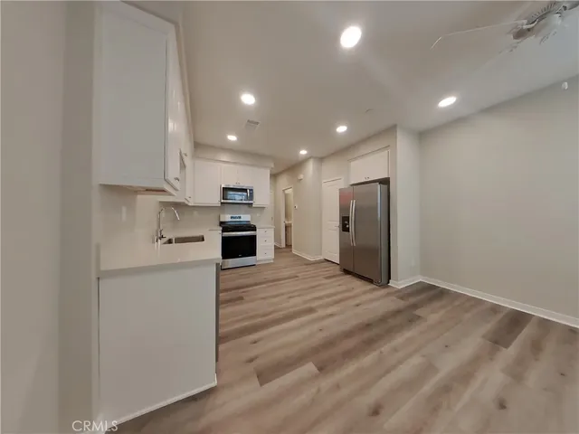 a view of kitchen with refrigerator and white cabinets