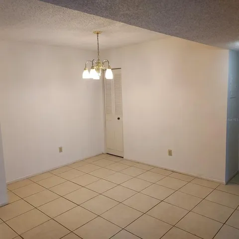 an empty room with a chandelier fan and wooden floor