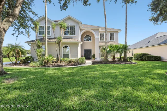front view of house with a yard and palm trees