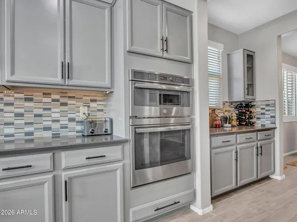 a kitchen with stainless steel appliances kitchen island granite countertop a dining table chairs refrigerator and cabinets