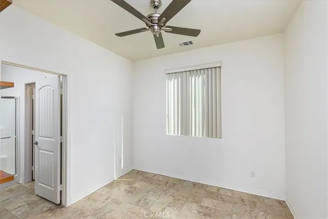 an empty room with windows and fan