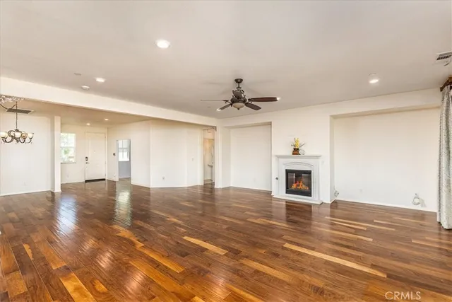 a view of a livingroom with a fireplace a ceiling fan and windows