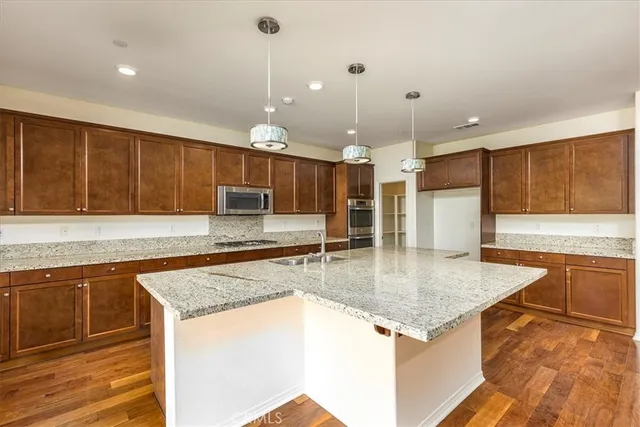 a kitchen with stainless steel appliances granite countertop a sink a oven a counter space and cabinets