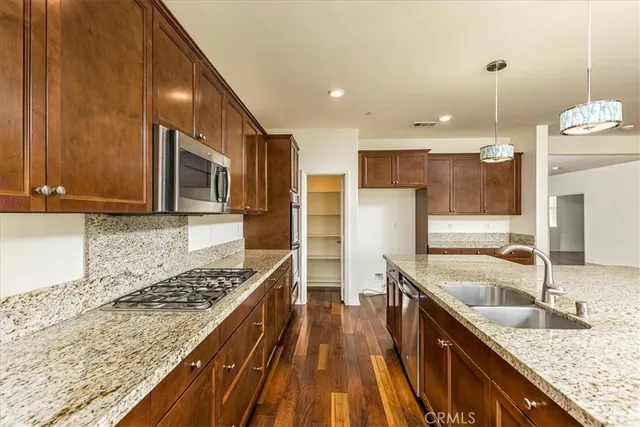 a kitchen with granite countertop kitchen island stainless steel appliances a sink stove and cabinets