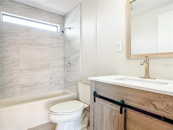 a bathroom with a granite countertop sink a toilet a mirror and bathtub