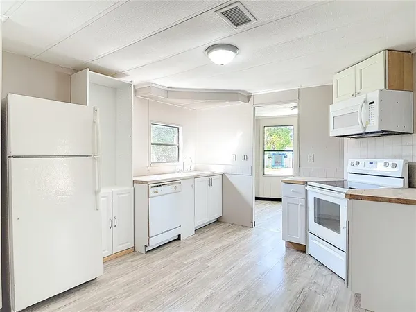 a kitchen with a refrigerator a sink and wooden floor