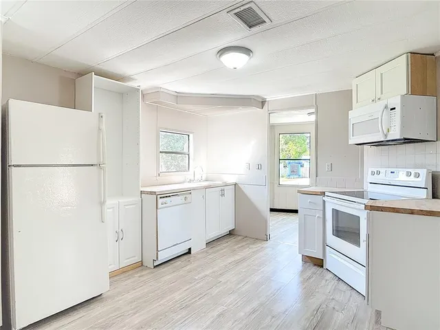 a kitchen with a refrigerator a sink and wooden floor