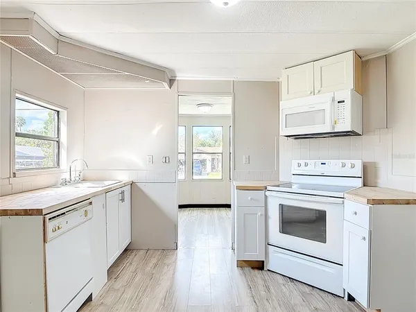 a kitchen with a stove a sink and wooden floor